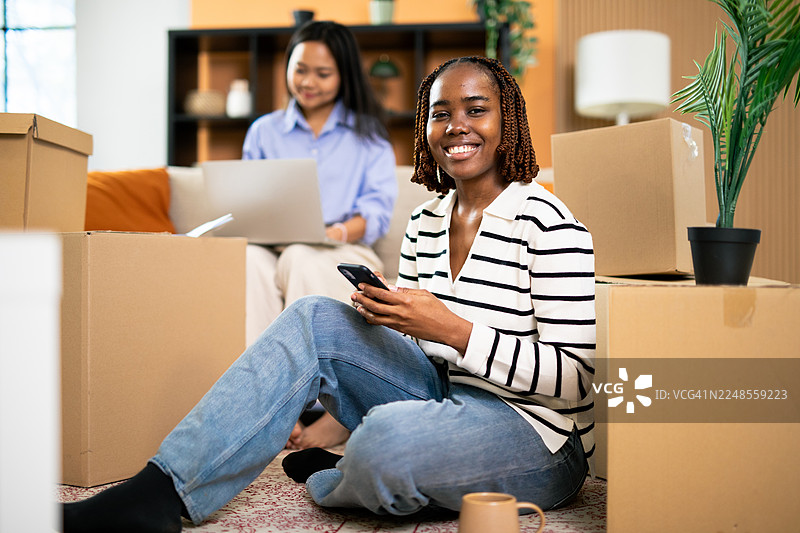 搬入新家，一位开心的黑人女性正在使用手机图片素材