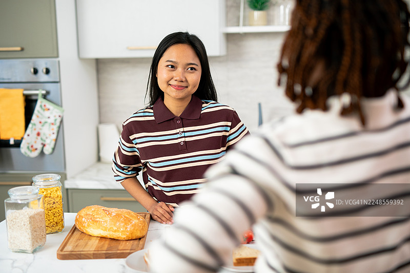 年轻女子在厨房与朋友愉快地交谈图片素材