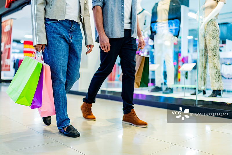 情侣在商场ATM机旁提着购物袋的低角度镜头图片素材
