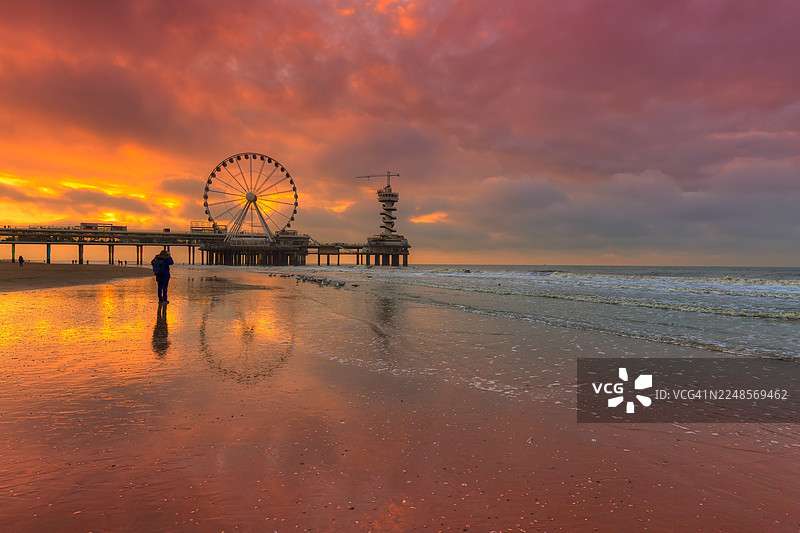 夕阳下的斯海弗宁恩码头倒映在湿沙上图片素材