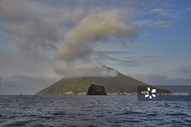 斯特龙博利岛及近海的斯特龙博利基奥小岛，一座火山岛，蓝天上飘着朵朵白云，海面平静，联合国教科文组织世界遗产，埃奥利群岛，西西里岛，意大利图片素材