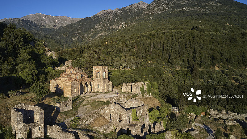 无人机视角,圣索菲亚教堂(公元14世纪),历史悠久的教堂和废墟,远眺蓝天下的森林山脉,米斯特拉斯,米斯特拉,联合国教科文组织世界遗产,拜占庭中世纪遗址城市,斯巴达西北部,泰格特山麓图片素材