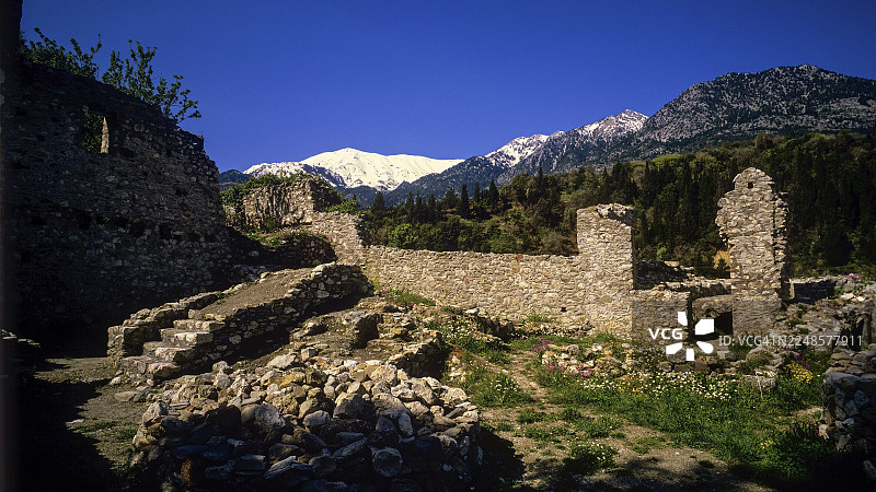 古老的石头遗迹城墙，背景为山峦，天空晴朗，地点为米斯特拉斯，联合国教科文组织世界遗产，中世纪拜占庭遗址城市，位于斯巴达西北部，泰格托斯山脉的余脉，伯罗奔尼撒半岛，希腊图片素材