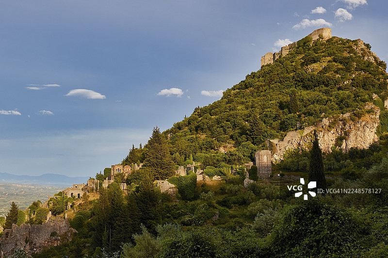 拜占庭遗址，绿色的山丘上散布着古老的遗迹，天空湛蓝，位于希腊伯罗奔尼撒半岛的斯巴达西北部，泰格特斯山脚下，是联合国教科文组织世界遗产地，中世纪拜占庭风格的废弃城市。图片素材