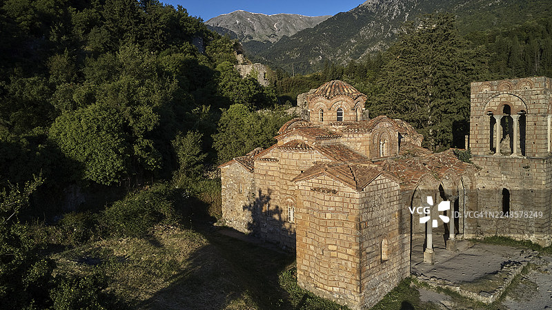 无人机视角,公元14世纪的圣索菲亚教堂,一座古老教堂,前景是废墟,背景是阳光下的山脉,位于斯巴达西北部的米斯特拉,米斯特拉,联合国教科文组织世界遗产,中世纪拜占庭废墟城市,位于山麓图片素材