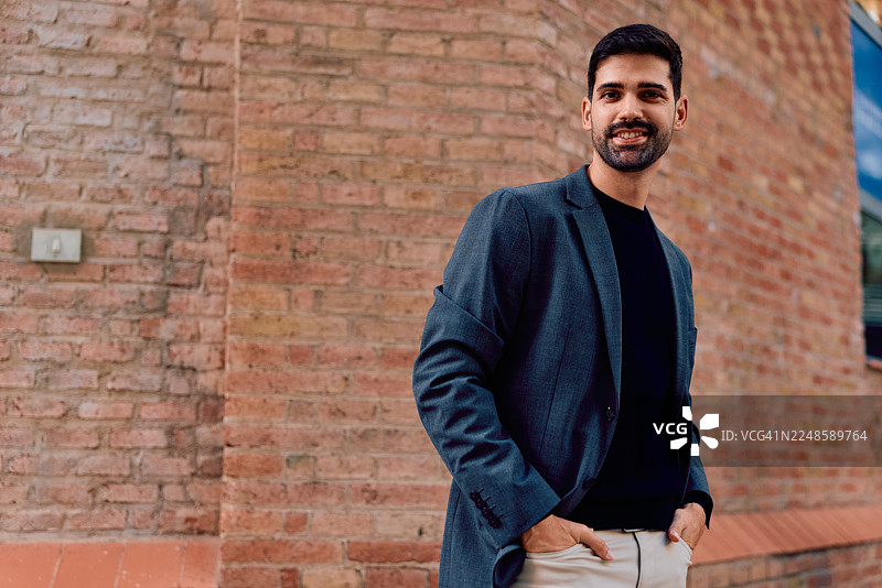 自信的年轻男士，穿着西装外套，在户外微笑着图片素材