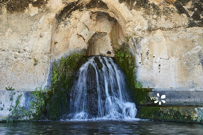 宁芙石窟，溪水从长满苔藓的岩石洞穴中流出，位于意大利西西里岛锡拉库萨的意大利那不勒斯考古公园。图片素材