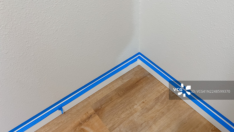蓝色的美纹纸胶带贴在白墙和木地板的角落，准备油漆或翻新图片素材