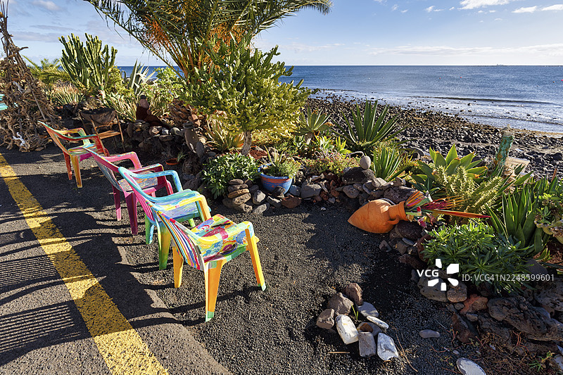 路边四把色彩鲜艳的塑料椅子并排摆放，地点：西班牙兰萨罗特岛亚伊萨的普拉亚克马达图片素材