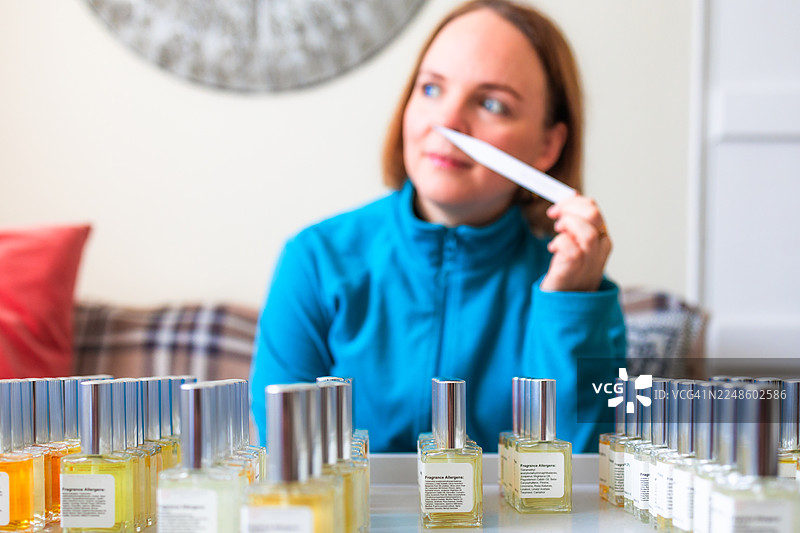 年轻的女调香师在家中使用试香纸闻香水图片素材