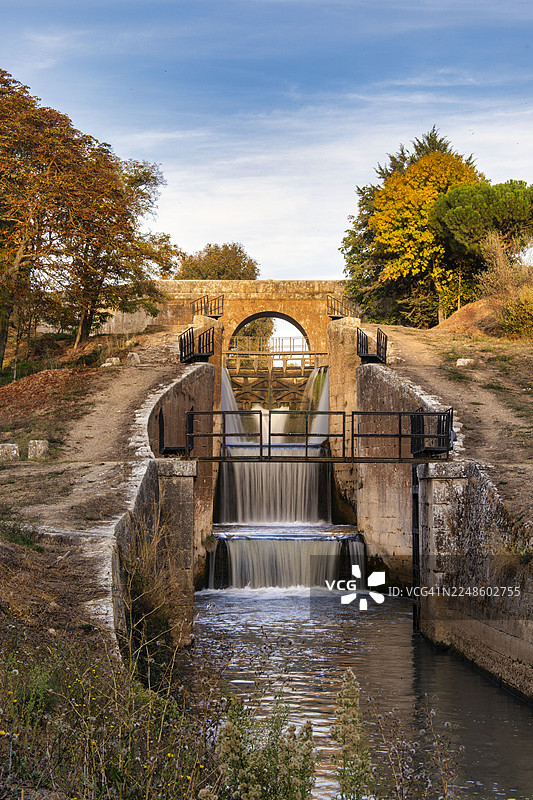 秋季，西班牙里瓦斯德坎波斯，历史悠久的石桥和运河，水流潺潺，景色宁静的自然风光图片素材