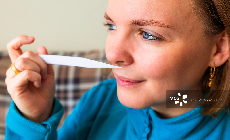 年轻女性调香师用闻香纸近距离闻香水的特写图片素材