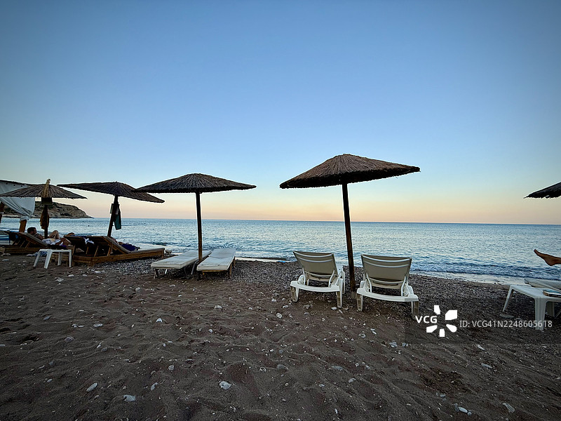 希腊斯特格纳海滨的宁静海滩风光，有躺椅和遮阳伞，在黄昏时分提供了一个宁静的海边度假胜地，斯特格纳，希腊，阿罗玛斯特格纳图片素材