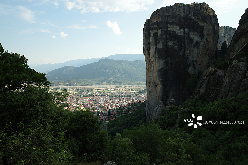 希腊卡兰巴卡，坐落在山谷中的城镇全景，四周环绕着雄伟的山脉和高耸的岩石，天空晴朗图片素材