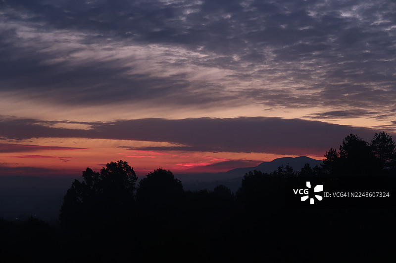 波斯尼亚和黑塞哥维那，前景为剪影树木和山脉的戏剧性日落天空图片素材