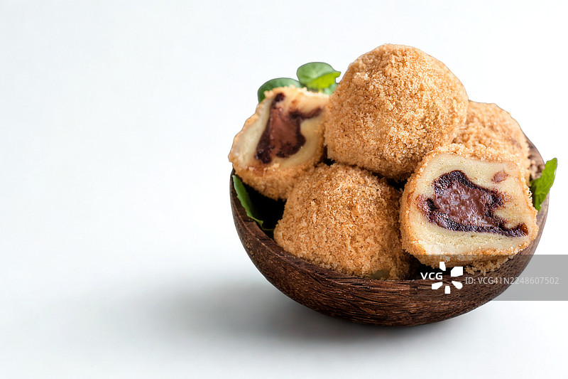 白色背景下的木碗中近景的黄豆粉麻糬甜点图片素材