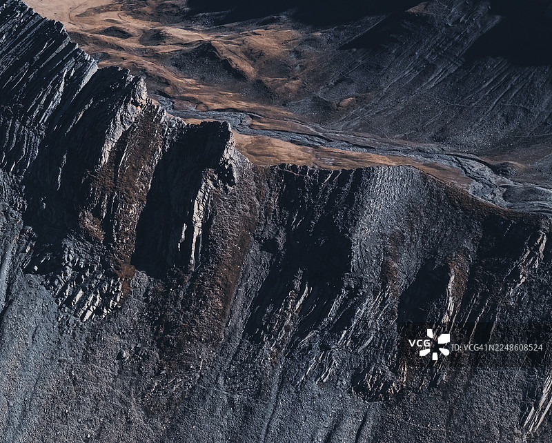 法国塔德瓦（Tardevant）地区，戏剧性的航拍视角展示了崎岖的山坡和山谷，在严酷的光线下呈现出地质构造和自然纹理。图片素材
