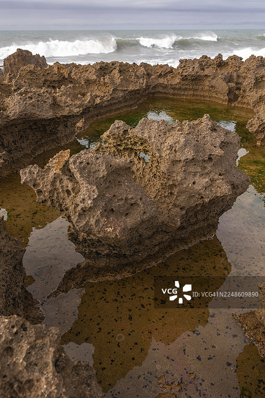 岩石散布在整个区域，其中一些又大又崎岖。海水看起来很汹涌。摩洛哥拉巴特图片素材