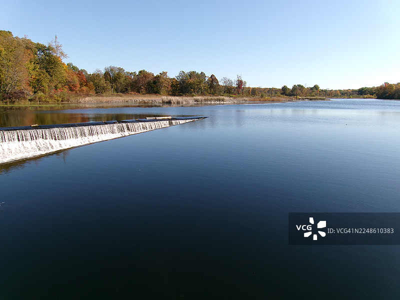 秋季湖泊美景，有小型瀑布和色彩斑斓的树木，天空湛蓝，地点为美国豪伊图片素材