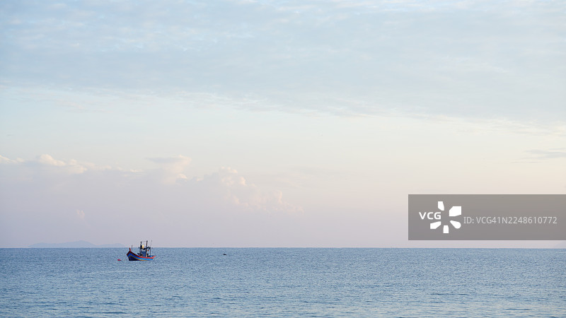 马来西亚宁静的海上日落，远方有渔船图片素材