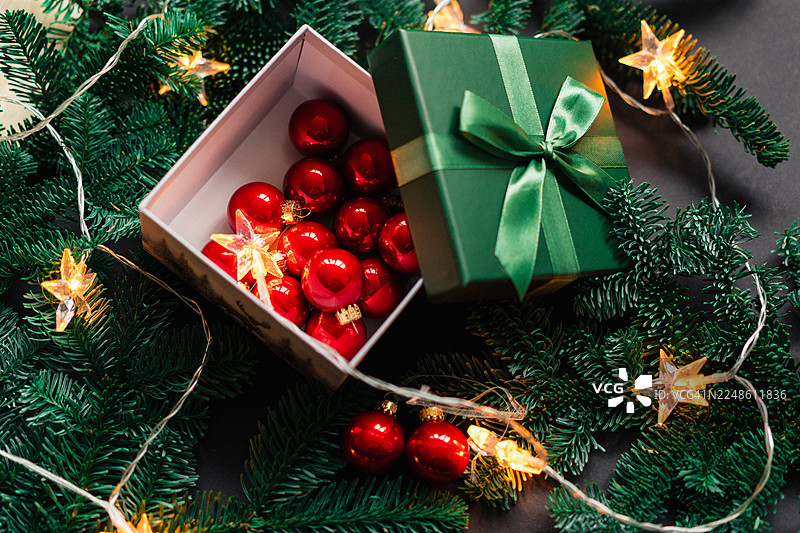 圣诞礼品盒，配有红色装饰品和绿色包装的礼物，摆放在节日常青树下图片素材