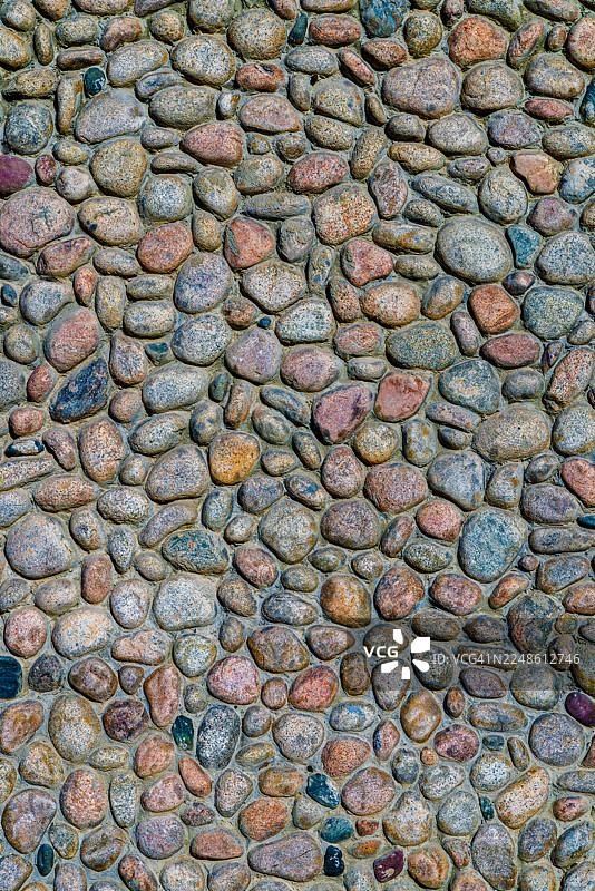 各种圆形彩色卵石和岩石砌成的石墙全景图，形成纹理背景图片素材