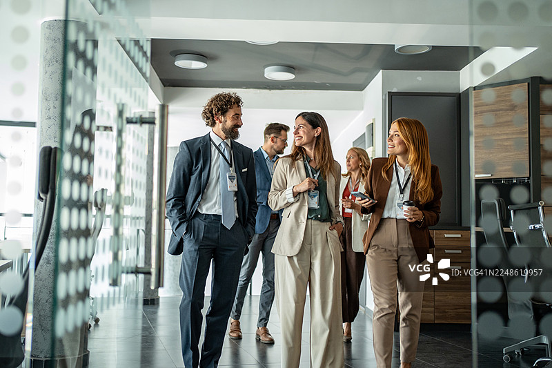商务专业人士在办公室走廊边走边谈图片素材