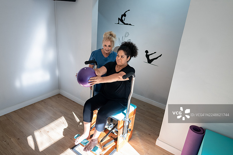 普拉提老师在普拉提课上帮助一位老年女性图片素材