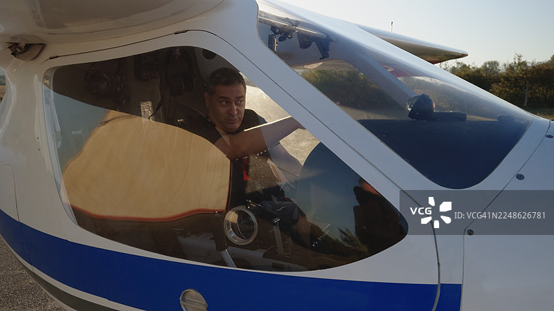 日出时，一位资深飞行员在他的私人飞机前准备起飞的肖像图片素材