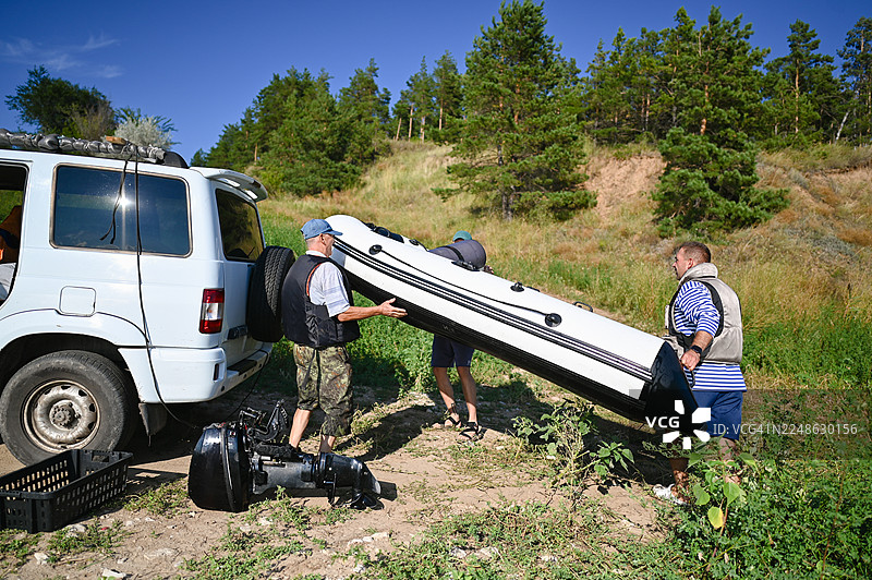男人们正扛着充气船走向水边，准备进行一次夏日旅行图片素材