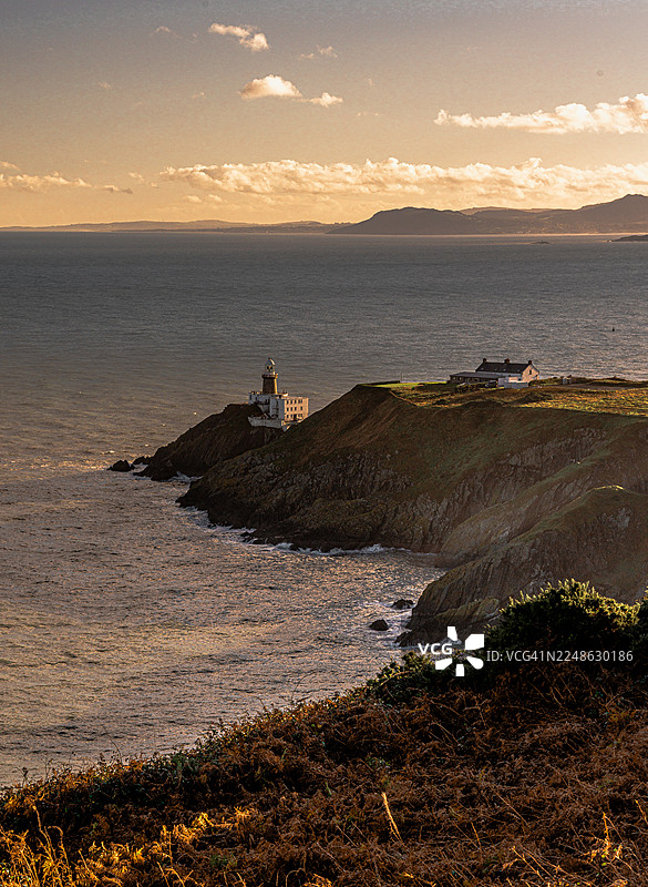爱尔兰霍斯，灯塔和海岸景观在戏剧性的日落天空下的风景图片素材