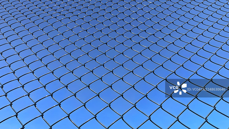 蓝天映衬下的铁丝网全景，强调安全与限制的概念图片素材