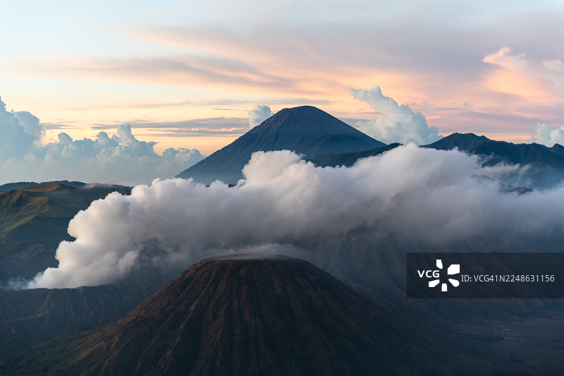 日落时分，印尼布罗莫火山，烟雾与云彩交织的戏剧性火山景观图片素材