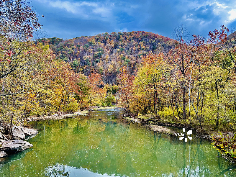 色彩鲜艳的秋叶倒映在宁静的河流中，河流穿过森林山谷，位于美国兰辛新河峡谷国家公园和保护区。图片素材
