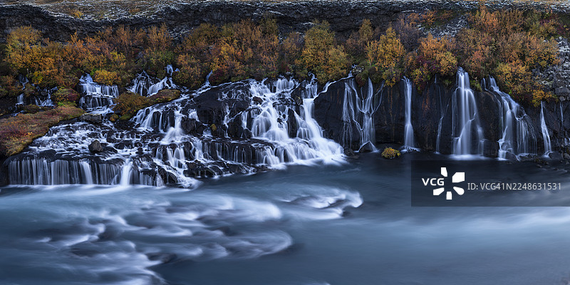 冰岛秋季，哈伦瀑布（Hraunfossar）倾泻在古老熔岩地貌上的令人惊叹的长曝光摄影图片素材