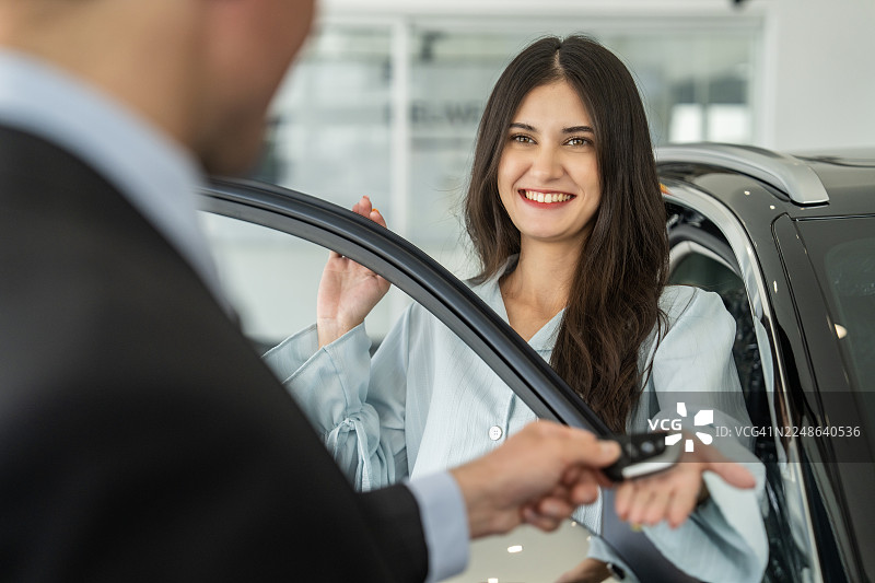 汽车销售人员将钥匙递给一位开心的女顾客图片素材