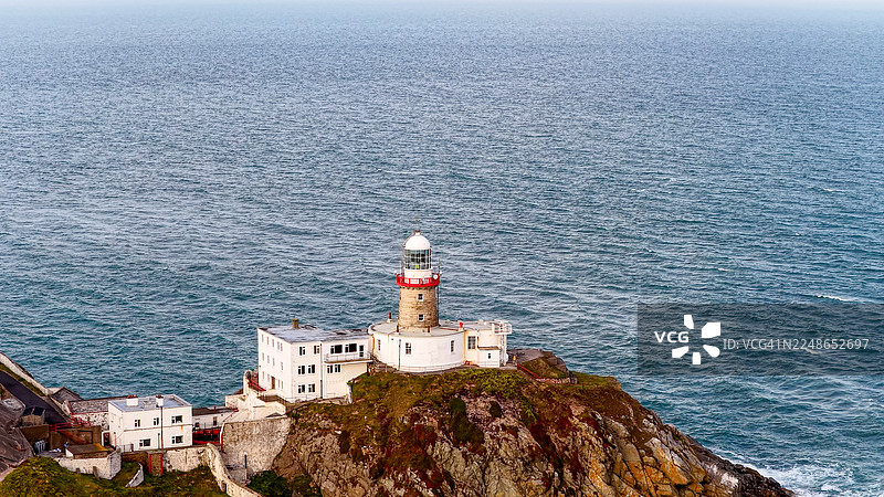 航拍都柏林霍斯海角半岛的贝利灯塔，历史悠久的海岸灯塔坐落在壮丽的海崖上，享有全景海景，象征着航海遗产和旅游业的导航与旅行概念图片素材