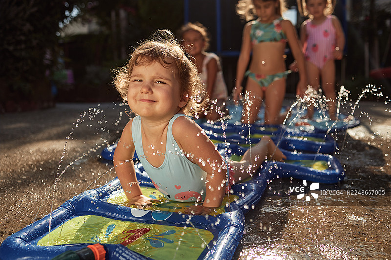 咧嘴笑的幼儿在戏水喷头垫上玩耍图片素材
