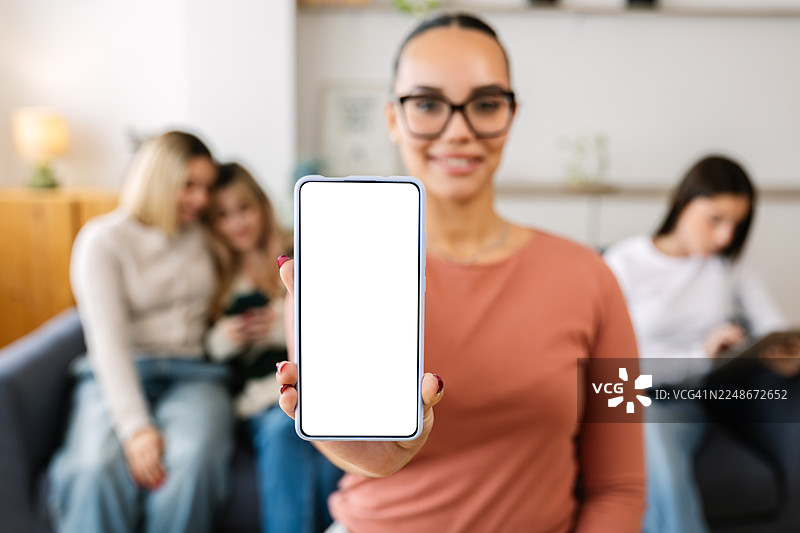年轻快乐漂亮的女性在家展示空白的智能手机屏幕图片素材
