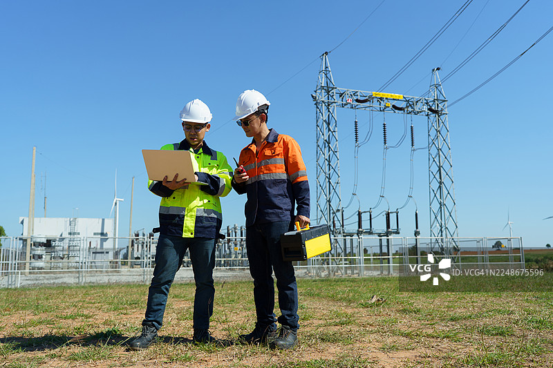 工程师正在检查一座大型风力涡轮机的运行情况，该涡轮机正在风力发电场发电。图片素材