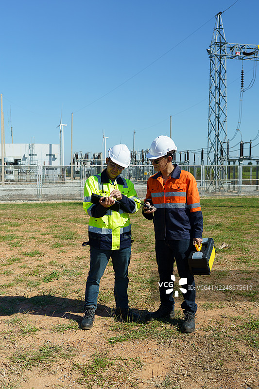 工程师正在检查一座大型风力涡轮机的运行情况，该涡轮机正在风电场中发电。图片素材