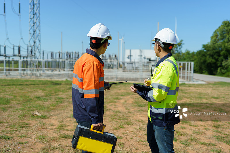 工程师正在检查一座大型风力涡轮机的运行情况，该涡轮机正在风力发电场中发电。图片素材