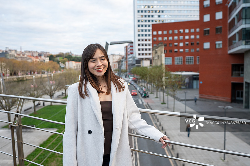 年轻女子在俯瞰毕尔巴鄂市的桥上微笑图片素材