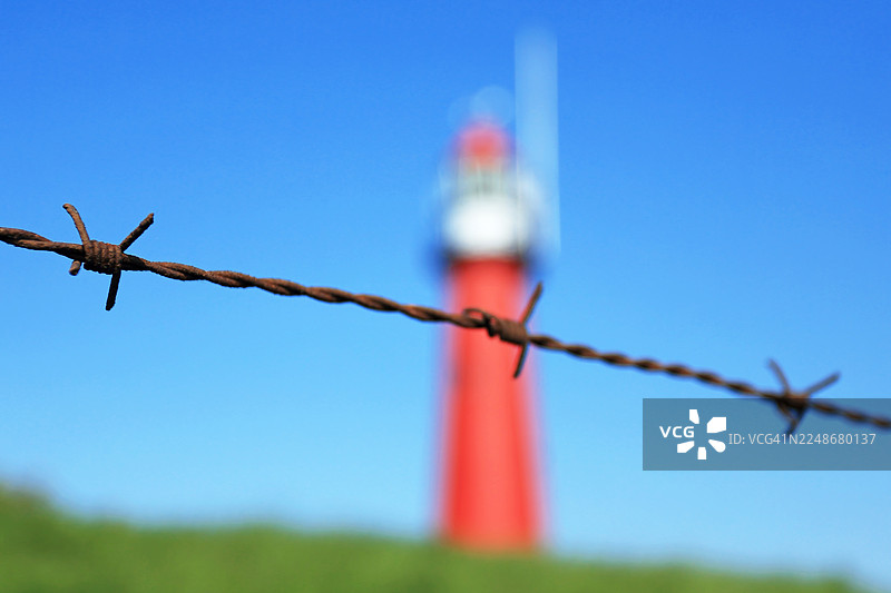 背景有红色灯塔的铁丝网图片素材