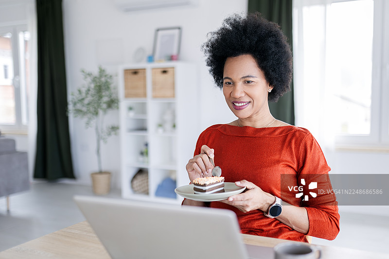 一位美丽的年轻非裔美国女性在家中放松地吃着蛋糕图片素材