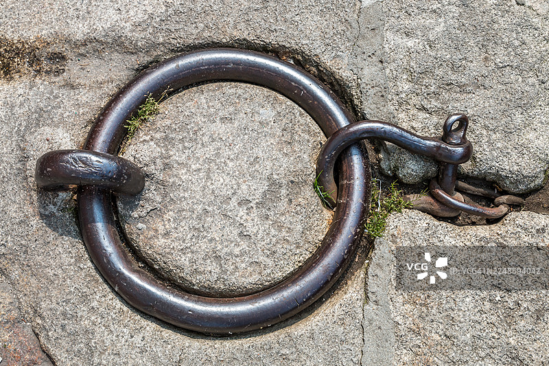 嵌在花岗岩码头上的带钩旧铁D形环图片素材