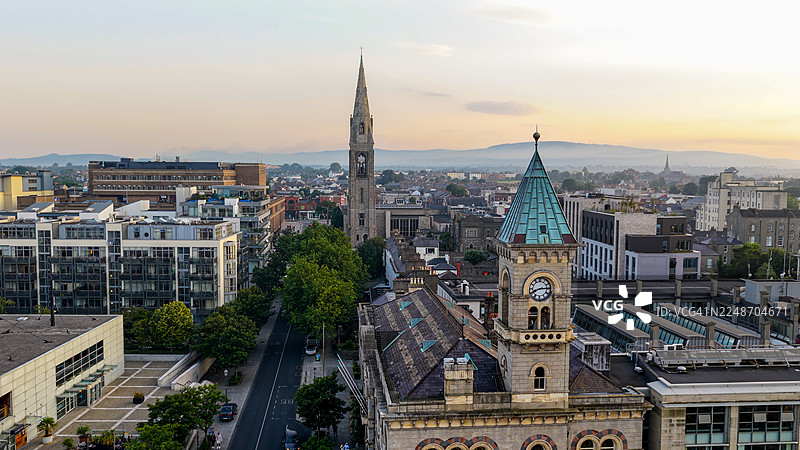日落时都柏林海岸郊区邓莱里镇中心的鸟瞰图， featuring 邓莱里-拉斯唐郡议会大楼和圣迈克尔教堂，拥有历史与现代建筑，城市景观和旅行概念图片素材