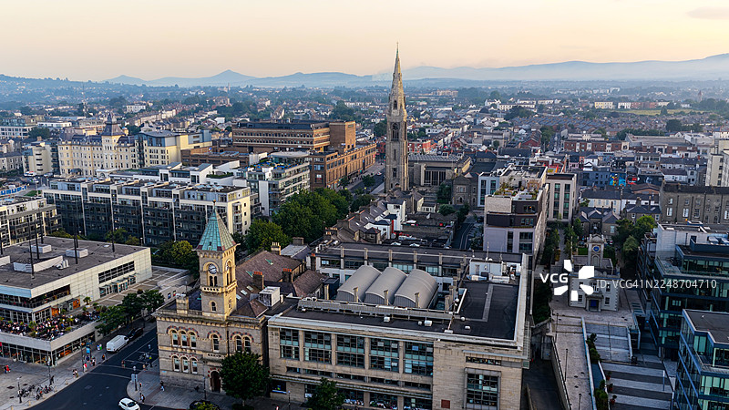 日落时都柏林海岸郊区邓莱里镇中心的鸟瞰图, featuring 邓莱里-拉斯当郡议会大楼和圣迈克尔教堂,具有历史与现代建筑风格,城市景观和旅行概念图片素材