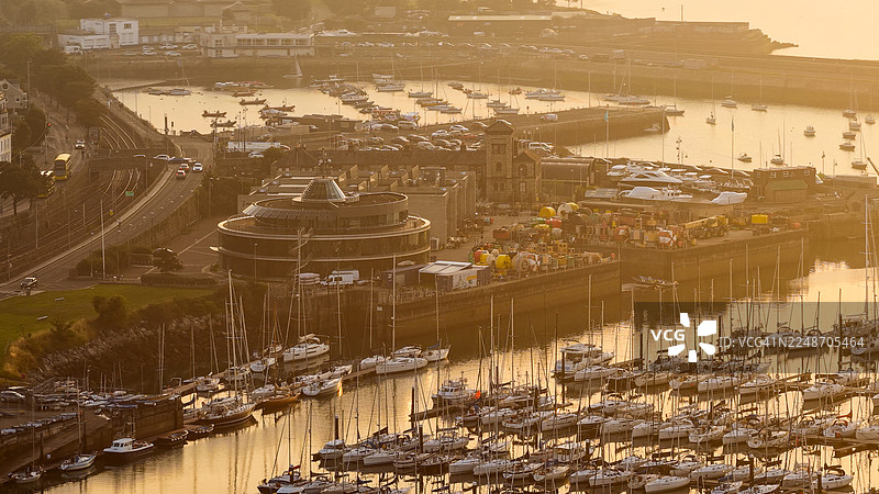 金色日落时邓莱里码头和海滨的鸟瞰图,都柏林沿海小镇,有游艇、弯曲的码头和爱尔兰海平静的倒影水面,爱尔兰旅游和社论设计的风景优美的海滨景观和旅行概念图片素材
