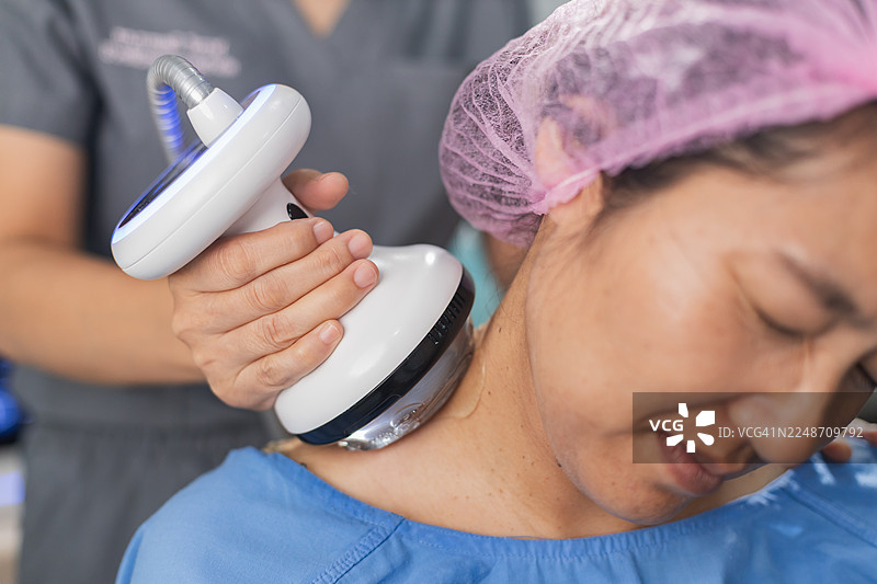 用于慢性疼痛缓解和康复概念的冲击波治疗探头在患者颈肩部位的特写。图片素材